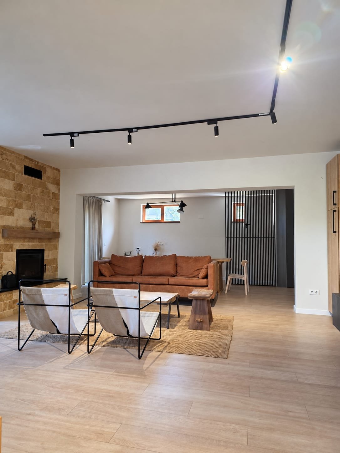Living luminos cu șemineu din travertin, fotolii design și canapea din piele